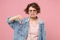 Dissatisfied young brunette woman girl in casual denim jacket eyeglasses posing isolated on pastel pink background Royalty Free Stock Photo