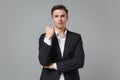 Dissatisfied young business man in classic black suit shirt posing isolated on grey wall background studio portrait Royalty Free Stock Photo