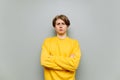 Dissatisfied young man in yellow clothes stands on a gray background with a sad face and looks at the camera. Isolated Royalty Free Stock Photo