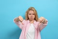 Dissatisfied young woman showing thumbs down on light blue background Royalty Free Stock Photo