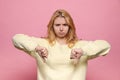 Dissatisfied young woman showing thumbs down on pink background Royalty Free Stock Photo