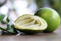Dissect lime is squeeze out with full lime and the leafs on the wooden table.