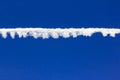 Dissolving airplane smudge against deep blue sky