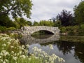 In the distance a Beautiful Stone wall bridge over a river in a pretty park surrounded by nature