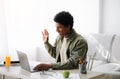 Distance communication concept. Positive black teen guy talking to his tutor or fellow students, waving at laptop webcam Royalty Free Stock Photo