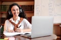 Woman sitting at desk, using laptop and writing in notebook Royalty Free Stock Photo