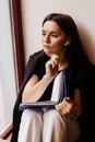 Distance learning. Attractive girl with book in cafe. Concentrated English teacher writes notes before online lesson via Royalty Free Stock Photo