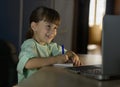 Happy girl learn english language online with laptop at home. Little girl looks at laptop