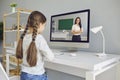 Distance learning education. A little girl listens to a teacher video lecture online in a laptop at the table at home. Royalty Free Stock Photo