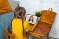 Distance learning. Funny young girl kid in yellow shirt using tablet and talking with teacher at home Royalty Free Stock Photo