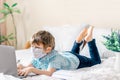 Distance learning online education. Caucasian boy in medical mask studying at home with digital tablet laptop notebook and doing Royalty Free Stock Photo