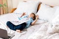 Distance learning online education. Caucasian happy boy lying with book studying home with laptop notebook and doing homework. Royalty Free Stock Photo