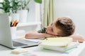 Distance learning online education. Caucasian kid boy study at home at laptop, tired sleep and napping on notepad, doing Royalty Free Stock Photo