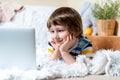 Distance learning online education. Caucasian smile kid boy studying at home with tablet laptop notebook and doing Royalty Free Stock Photo