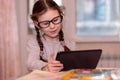 Distance learning online education.School girl with glasses does homework on tablet at home.Quarantine Royalty Free Stock Photo