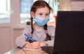 Distance learning online education.School girl in medical mask does homework on laptop at home.Quarantine Royalty Free Stock Photo