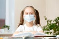 Distance learning online education.School girl in medical mask does homework o at home.Quarantine