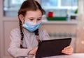 Distance learning online education.School girl in medical mask does homework on tablet at home.Quarantine Royalty Free Stock Photo