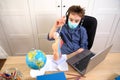 Distance learning online education. schoolboy in medical mask studying at home, working at laptop notebook and doing school Royalty Free Stock Photo