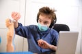 Distance learning online education. schoolboy in medical mask studying at home, working at laptop notebook and doing school Royalty Free Stock Photo