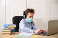 Distance learning online education. schoolboy in medical mask studying at home, working at laptop notebook and doing school Royalty Free Stock Photo