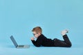 Distance learning online education. Schoolboy studying at home with laptop and doing school homework on blue background Royalty Free Stock Photo