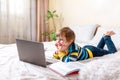 Distance learning online education. Smiling boy with book studying at home with digital tablet laptop and doing school Royalty Free Stock Photo