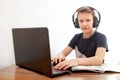 Distance learning in quarantine. A boy in headphones in front of a computer does his homework Royalty Free Stock Photo