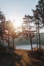 Distance view. Morning landscape. Pine forest, sun rays, glow, river lake, mountains. Summer camping warm colors. Tourism and Royalty Free Stock Photo