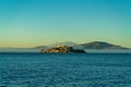 Distant alcatraz insland on the ocean with mist and fog and background mountains in golden sunset or sunrise Royalty Free Stock Photo