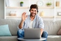 Distant communication concept. Smiling arab man in headset waving hand at laptop camera, making video call Royalty Free Stock Photo
