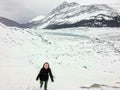 A distant faraway view of a female hiker alone walking through the vast winter landscape towards the athabasca glacier