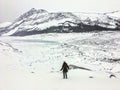 A distant faraway view of a female hiker alone walking through the vast winter landscape towards the athabasca glacier