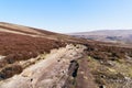 A distant group of people wlak up a rocky footpath on Derwent Moor