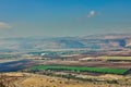 A distant panoramic view of an urban settlement with green farmland in the foreground and mountains beyond Royalty Free Stock Photo