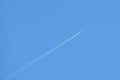 Distant passenger jet plane flying on high altitude on clear blue sky leaving white smoke trace of contrail behind. Air Royalty Free Stock Photo