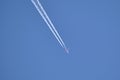 Distant passenger jet plane flying on high altitude on clear blue sky leaving white smoke trace of contrail behind. Air Royalty Free Stock Photo