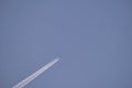 Distant passenger jet plane flying on high altitude on clear blue sky leaving white smoke trace of contrail behind. Air Royalty Free Stock Photo