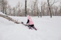 Distant photo of female Russian kid climbing tree log with efforts wearing pink winter clothes in forest. Astonishing Royalty Free Stock Photo