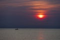 Distant photo of a small boat and an identifiable fisherman in silhouette. Sailing on the sea near the horizon There is a rising