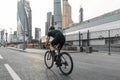 Athletic sportsman riding professional bike next to modern buildings on a road. Royalty Free Stock Photo