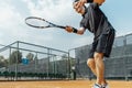 Young attractive man playing tennis at court and beating the ball with a racket. Royalty Free Stock Photo