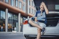 Distant plan of young man looking at map sitting in the truck of car. Royalty Free Stock Photo