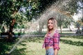 Distant portrait photo of adult shining blonde woman standing in park wearing checkered shirt tied in belly area in