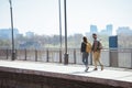 distant view of couple of stylish tourists with backpacks going at outdoor