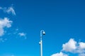 Distant view of a generic CCTV camera seen aloft on a tall metal pole. Royalty Free Stock Photo