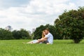 distant view of redhead couple sitting on grass