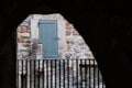 Distant view of a very old wooden door seen from within a nearby, dark tunnel. Royalty Free Stock Photo