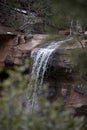 Distant View of Water Falling Over Red Sandstone Cliffs with Branches in Winter Royalty Free Stock Photo