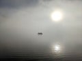 Distinct view of a silhouette of people on a boat in the middle of the sea on a foggy day